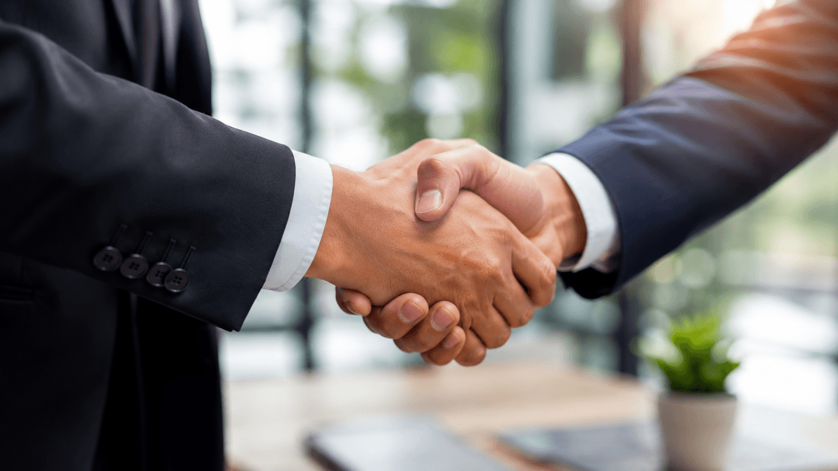Close up of a professional handshake in a modern office, bright natural light, business attire, focus on the handshake, trust and partnership atmosphere.